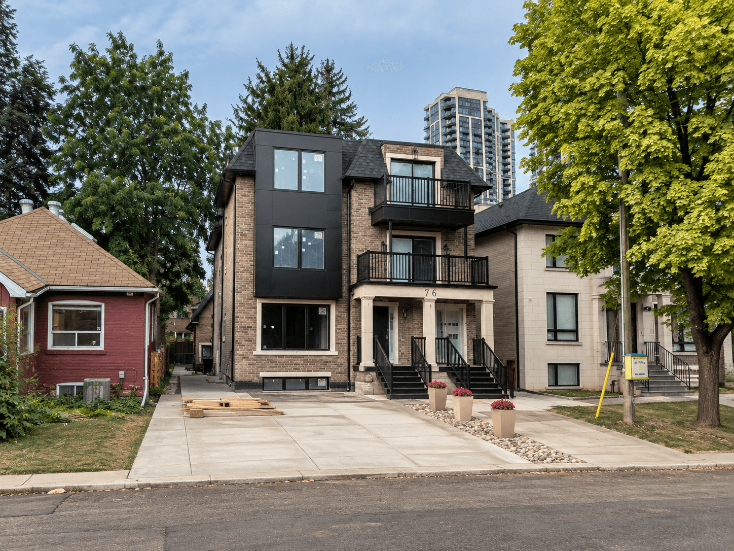 North York 01 latest exterior progress with dark facade panels, balcony railings, and paved driveway
